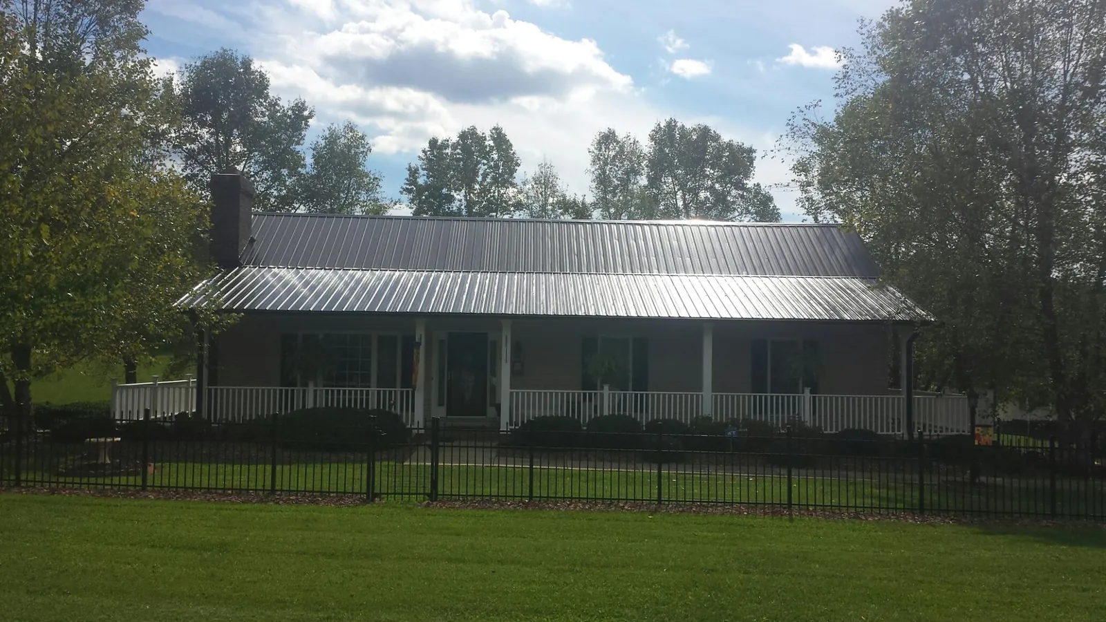 Gray metal roof on a brick ranch with a full width front porch — Gutter Guard Installation work by our crew in Middleburg